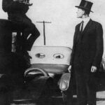 Grosser Mann wird fotografiert vom Fotograph der auf Auto sitzt