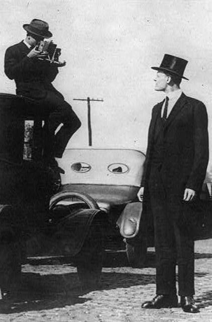 Grosser Mann wird fotografiert vom Fotograph der auf Auto sitzt
